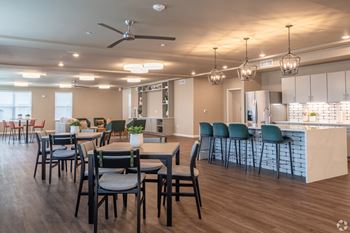 a large dining room with tables and chairs and a kitchen